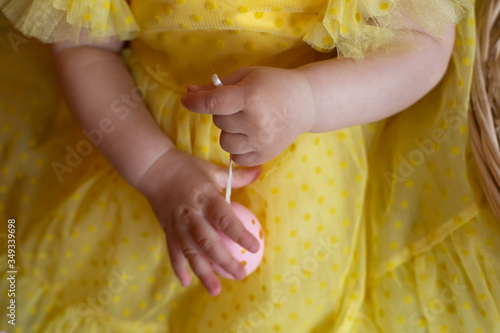 a girl in a yellow dress holds a toy. child's hand