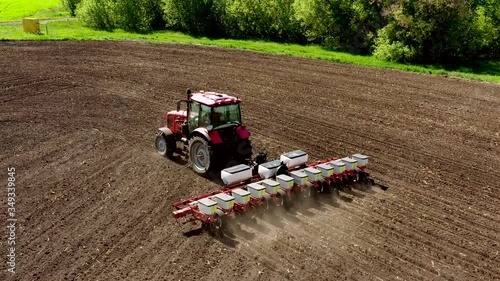 aerial view tractor cuts furrows in farm field for sowing farm tractor with rotary harrow plow preparing land for sowing. Tractor with harrows prepares the agricultural land for planting crop