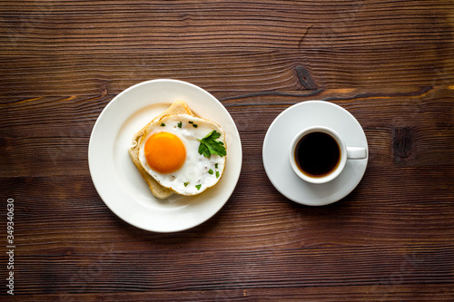 Fried eggs sandwich on plate - dark wooden dinner table top view