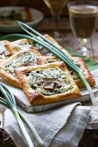 Puffs with cheese, spinach and mushrooms, served with wine and green onions. Rustic style. photo