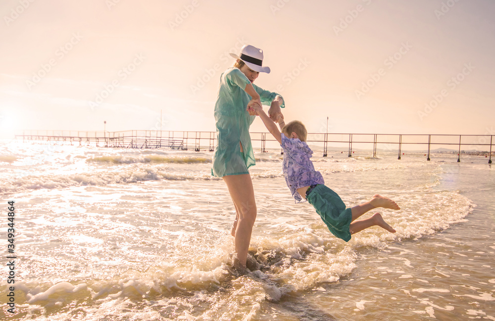 mother and children are playing in the sea on the beach