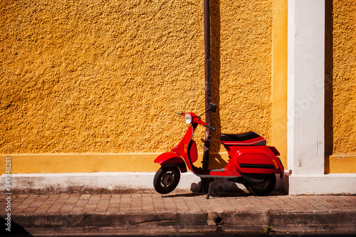 Photography Red retro scooter is parked on old street in Rome, Italy