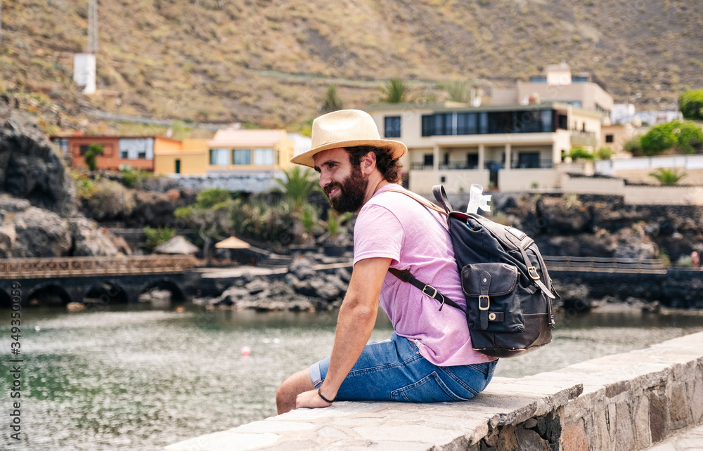 A tourist man with hat and backpack through a village on the coast of El Hierro, Canary Islands