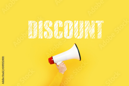 megaphone in hand and inscription discount on a yellow background