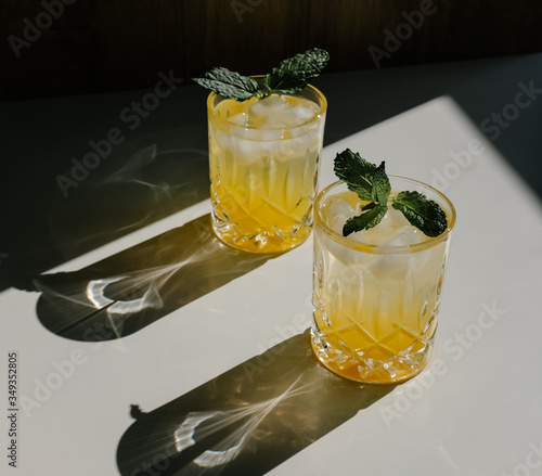 Refreshing iced yellow cocktails under sun with dark shades on white background. 