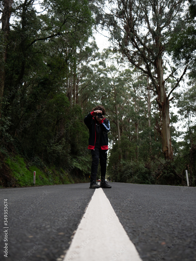 Person in forest taking photo on road