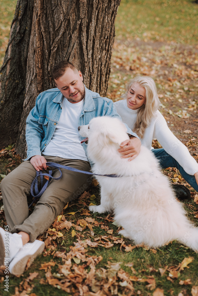 Man and woman enjoying weekend with dog, sitting near tree Man and woman enjoying weekend with dog, sitting near tree
