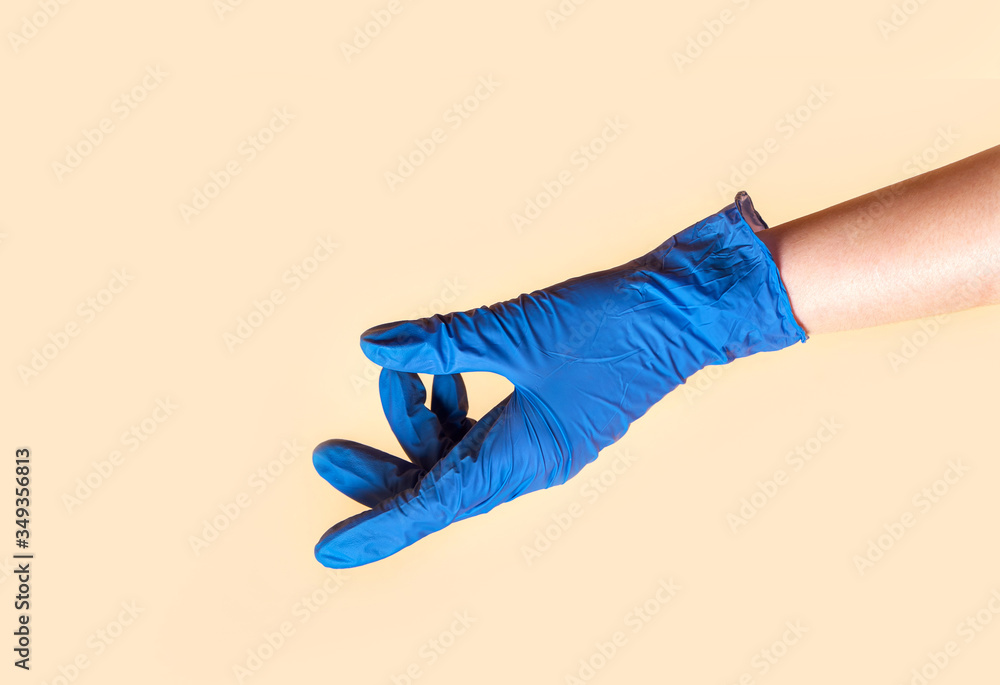 Empty open female hand in blue medical gloves on a beige background. Female hand showing something Empty open female hand in blue medical gloves on a beige background. Female hand showing something