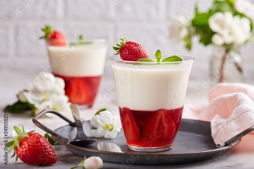 Layered dessert in glass with vanilla panna cotta and jelly with strawberries