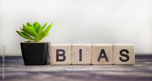 Bias - concept on a white background. Wooden cubes with green flower photo