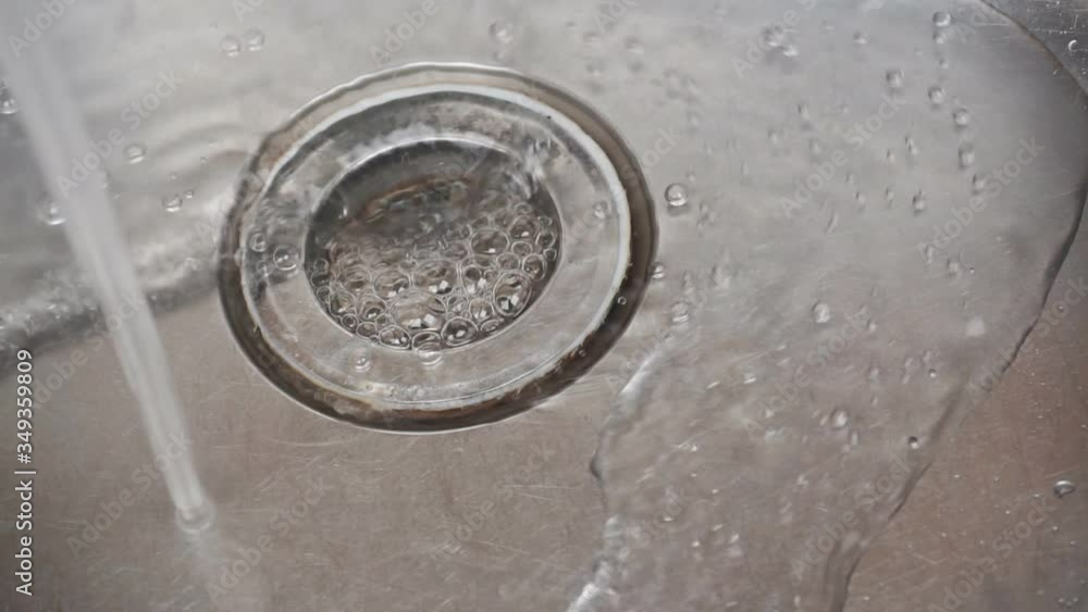 A stream of water flows into a stainless steel sink.