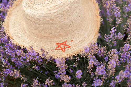 Straw hat with a red star. Wicker hat in lavender flowers field
