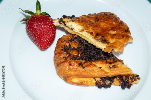 Chocolate chips croissant on white plate. Close up. A braid with chocolate .Swiss Brioche with Chocolate Chips (Brioches suisses). . photo