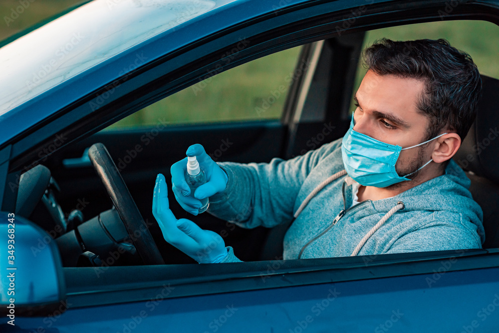 Young man using hand sanitizer or alcohol gel for washing hands in the car. Young man using hand sanitizer or alcohol gel for washing hands in the car.