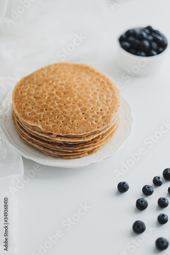 Homemade pancakes with fresh blueberries in a white plate on a white background.