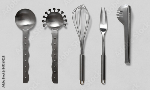 Salad spoon, whisk, meat fork and pasta tongs, cutlery on a white background