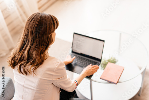 Young casual beautiful woman working on a laptop sitting on the sofa in the house, photo from above