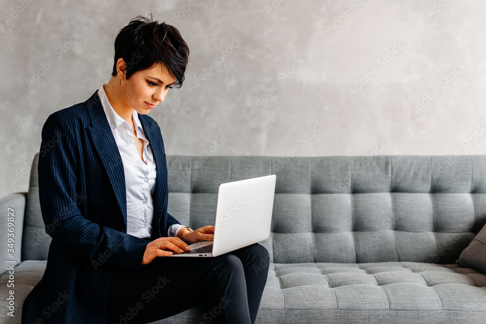 Young beautiful business woman looking at the laptop while working from home, sitting on the sofa Young beautiful business woman looking at the laptop while working from home, sitting on the sofa