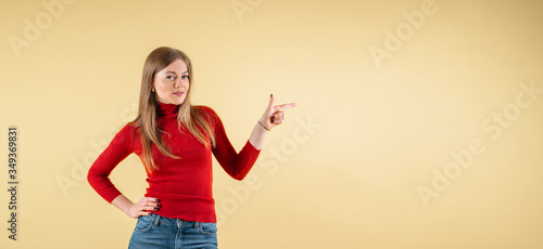 Smiling woman pointing finger. Isolated portrait of female business model on yellow background, banner size