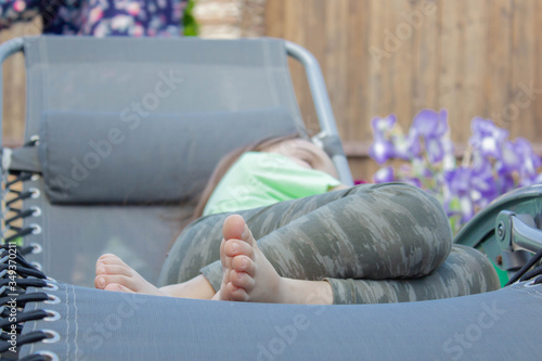 bare feet of a girl in pink on a chaise longue. the girl is resting in the sun. The concept of relaxation.