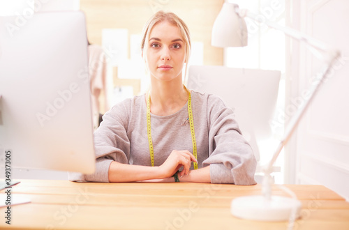 Fashion designer woman working in studio, sitting at thhe desk photo