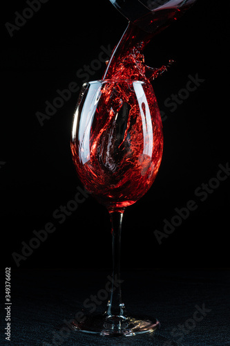 Wine. Red wine pouring into a wine glass. Isolated on black background.