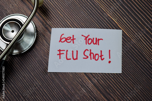 Get Your Flu Shot! write on sticky note isolated on wooden table.