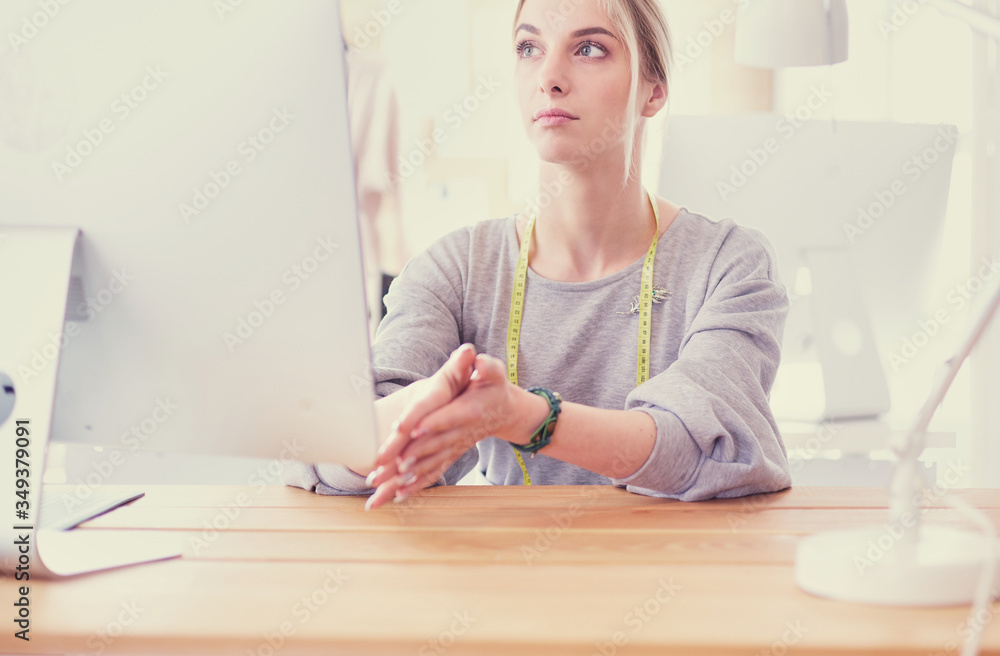 Fashion designer woman working in studio, sitting at thhe desk Fashion designer woman working in studio, sitting at thhe desk