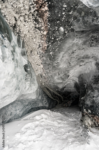 Inside of an ice cave with snow on the ground and rocks on top; end of a tunnel in Matanuska Glacier, Alaska. Detail; taken in winter. photo