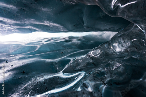Close up in the inside of an ice cave in Matanuska Glacier, Alaska. Details of the surface of the ice; texture. Looking up. Taken during a trek in winter holidays. Against the light. photo