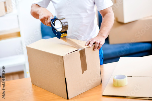 Worker hands holding packing machine and sealing cardboard or paper boxes photo