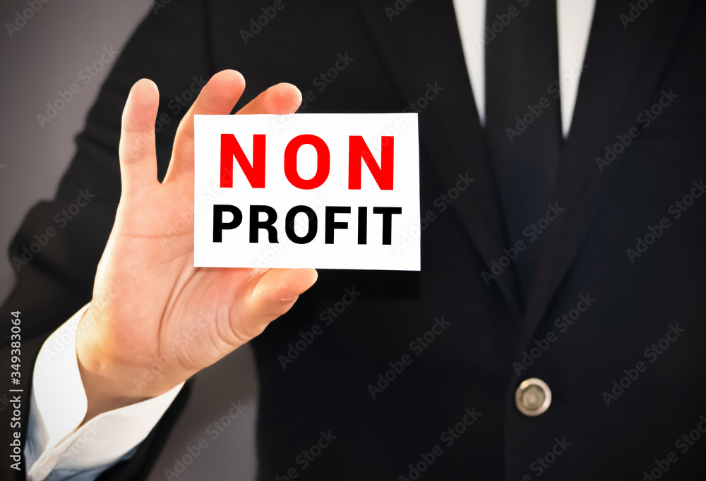 Businessman Holding Small White Signage Showing Non Profit Texts. Businessman Holding Small White Signage Showing Non Profit Texts.
