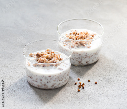 Breakfast buckwheat boiled with milk in a glass Cup on a light gray background