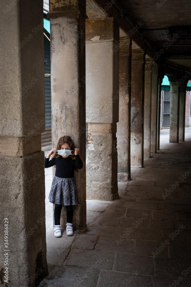 cute little girl covering her mouth with a surgical mask in Venice Italy