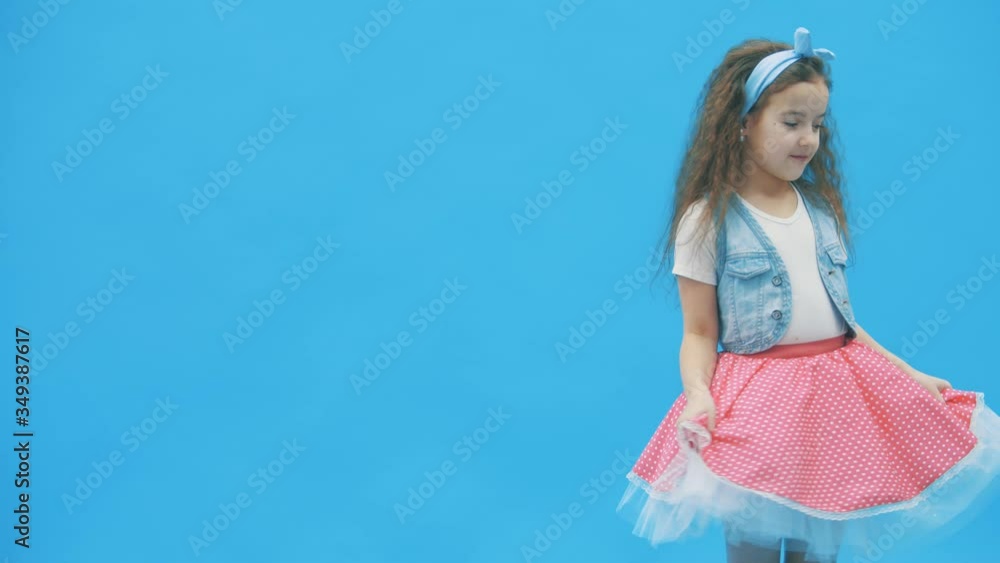 LIttle girl standing over blue background in 4k slowmotion video. LIttle girl standing over blue background in 4k slowmotion video.