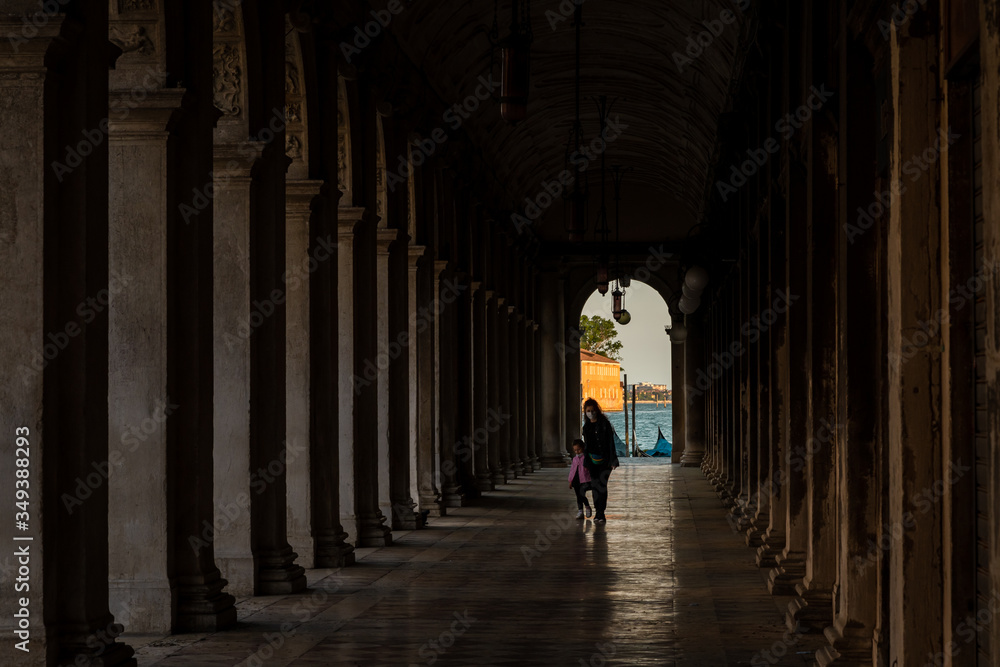 young mother and her daughter walking under the arcades in venice