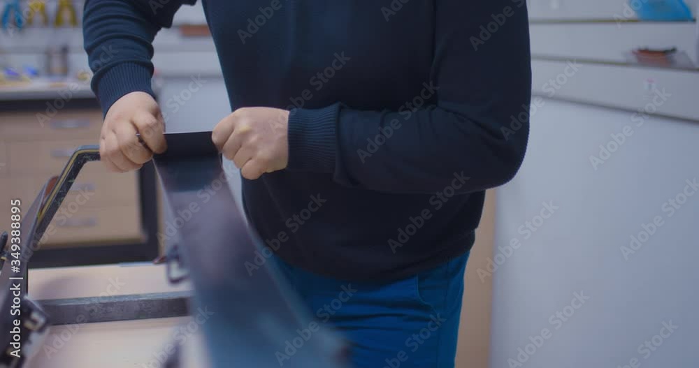 Master’s hands remove the unnecessary layer of skis with a scraper, preparing the ski equipment for the winter season. Unnecessary layer of skiing is removed with a scraper. Close-up. Master’s hands remove the unnecessary layer of skis with a scraper, preparing the ski equipment for the winter season. Unnecessary layer of skiing is removed with a scraper. Close-up.