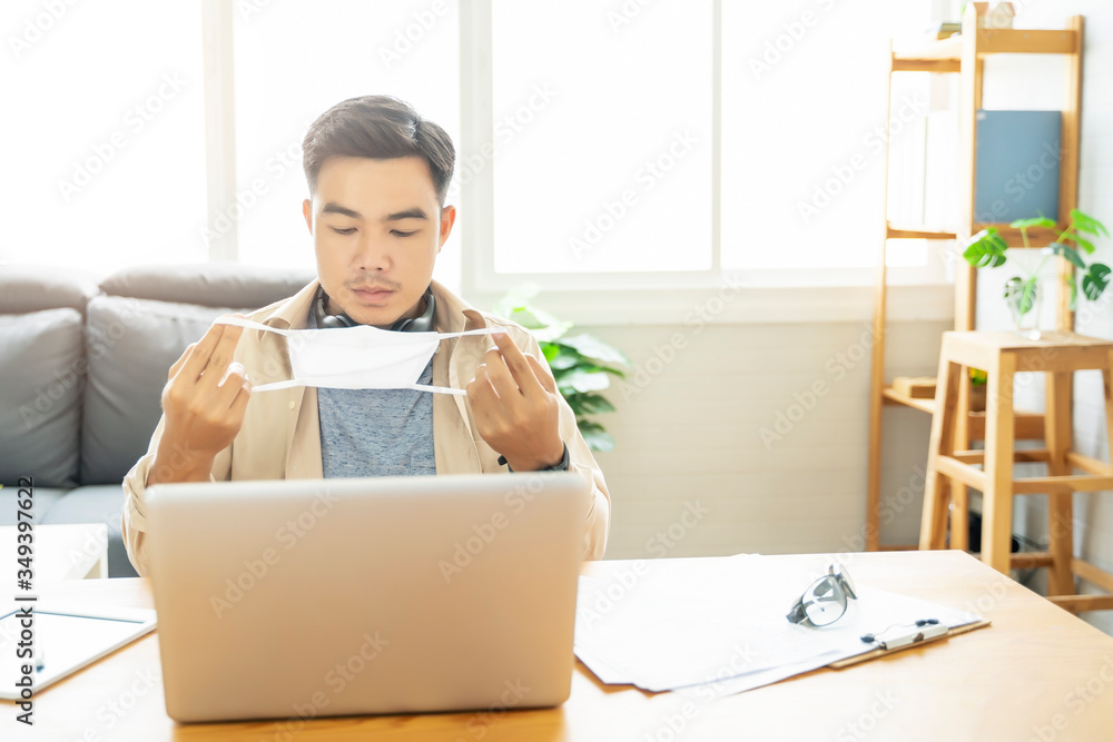 Asian man putting on protective mask Working from home web designing graphical user interface UX UI, in home office using computer laptop designing creative planning innovative idea, in quarantine Asian man putting on protective mask Working from home web designing graphical user interface UX UI, in home office using computer laptop designing creative planning innovative idea, in quarantine