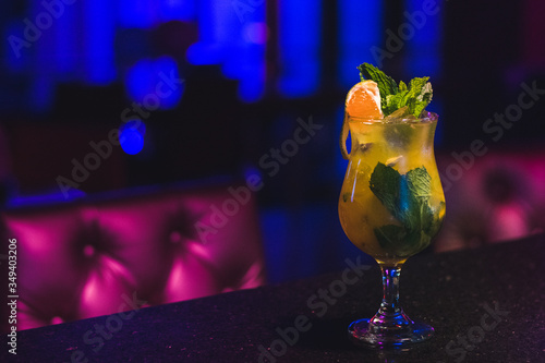 Copa coctel naranja yerbabuena sobre barra de bar fondo azul. photo