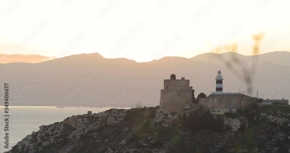 ancient building lighthouse on a rock in Sardinia Italy with sea and mountains at sunset