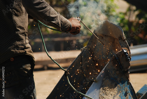indian Welder welding metal at street workshop with flying sparks in uttar pradesh, India 