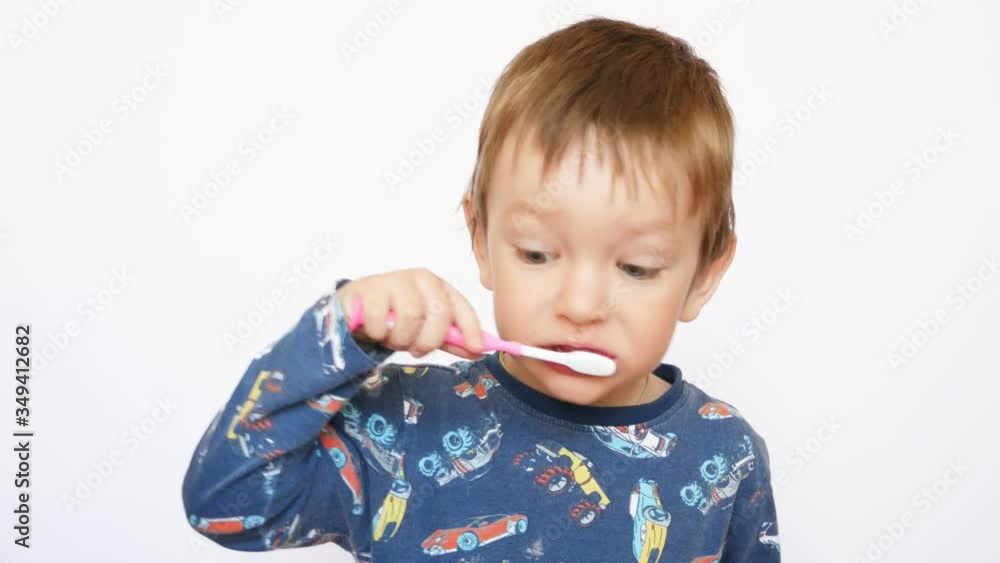 A beautiful little boy wearing pajamas brushes his teeth A beautiful little boy wearing pajamas brushes his teeth
