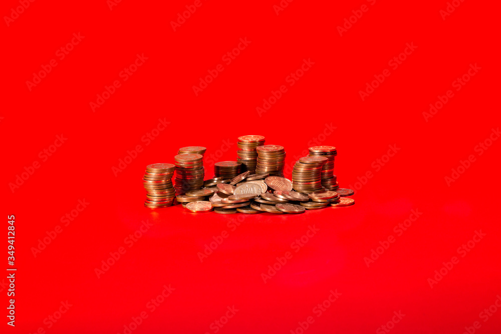 Coin cash stacks and fallen heap on a vibrant red coloured background. Piles of cash comprising of UK GBP Sterling one pence coins, centred allowing for copy space. Coin cash stacks and fallen heap on a vibrant red coloured background. Piles of cash comprising of UK GBP Sterling one pence coins, centred allowing for copy space.