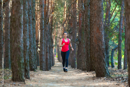 Young woman runner training alone outdoors in the summer forest