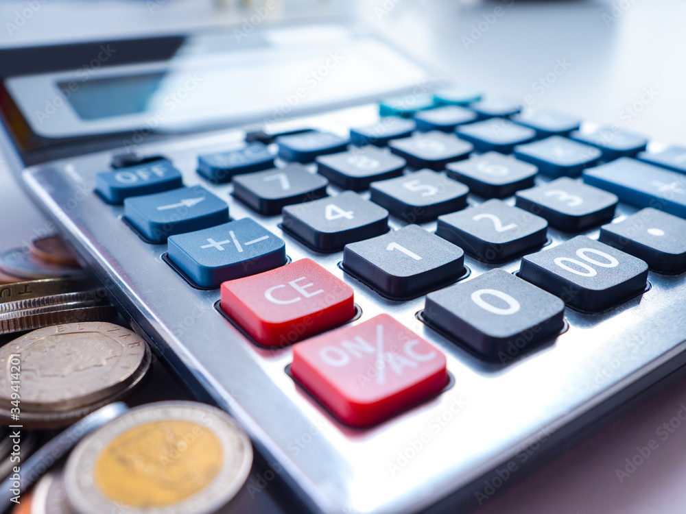 Calculator close-up on the background of coins. Family income and expenses. Balance between income, expenses, and savings. Rational spending. The budget of the household. Calculator close-up on the background of coins. Family income and expenses. Balance between income, expenses, and savings. Rational spending. The budget of the household.