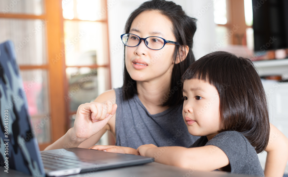 An Asian girl is learning online lessons from a notebook computer with her mother. An Asian girl is learning online lessons from a notebook computer with her mother.