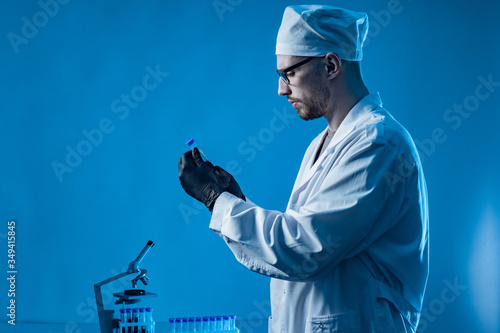 Doctor examines the patient blood. Laboratory assistant next to  microscope. Concept - blood test of the infected. Doctor conducts a test with blood. Test tube with tests in the hands of a doctor. photo