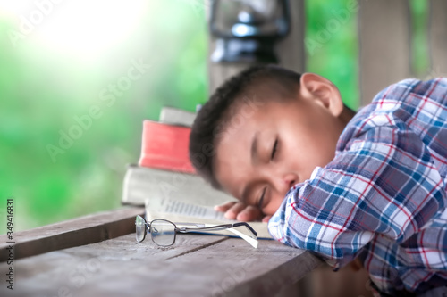 Close up eye glasses with boy resting after reading the Bible on wooden table, Christian concept.