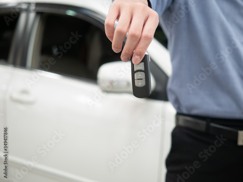 Man holding key in modern auto dealership. Close up hand of cardealer giving car key to customer. Car dealer with a key. Auto dealership and rental concept © natsarun