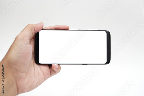 Hand with blank smart phone on landscape mode for mock up